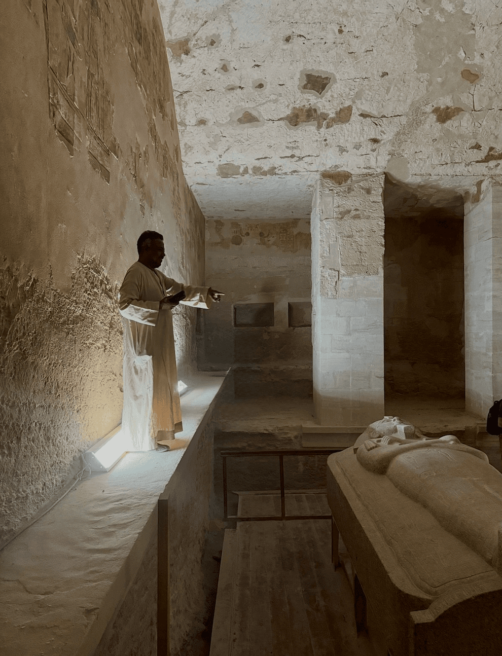 Expert guide explaining ancient sarcophagus in Egyptian tomb chamber during private tour