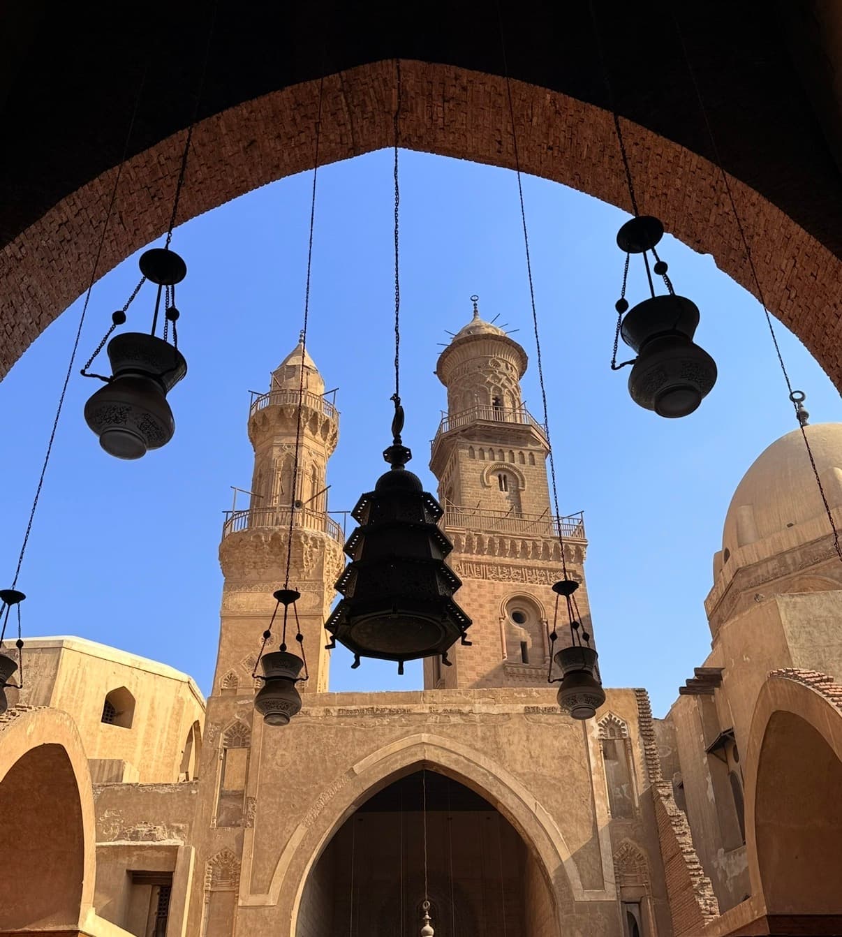 Historic mosque with minarets and traditional hanging lamps in Islamic Cairo