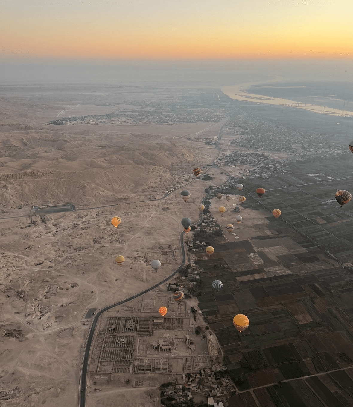 Hot air balloon ride over Valley of the Kings in Luxor at sunrise with aerial view of Nile River and desert mountains