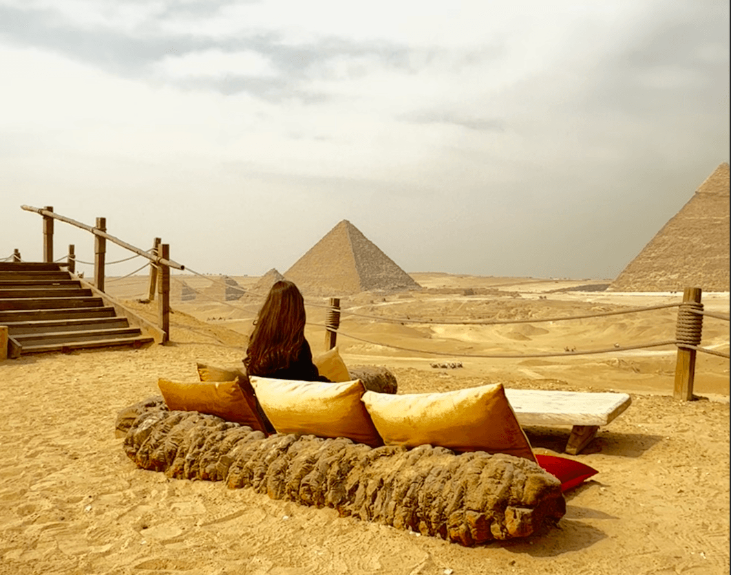 Scenic view of the Giza Pyramids from Khufu restaurant with traveler relaxing on cushions during Cairo highlights tour
