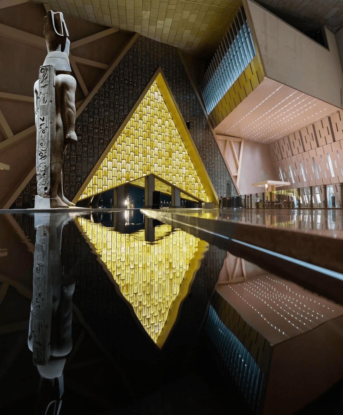 Grand Egyptian Museum interior with Ramses II statue and golden triangular architecture