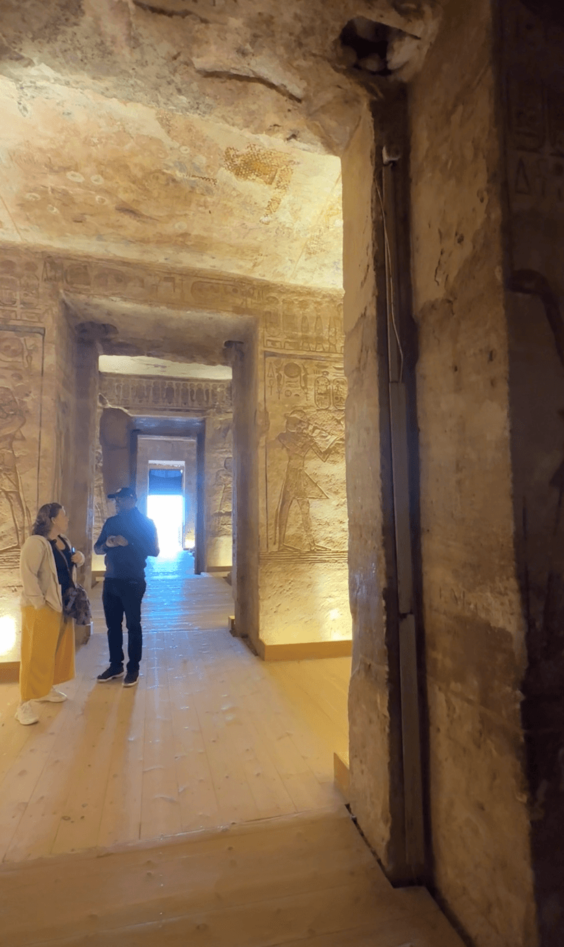 Expert guide leading travelers through ancient temple in Aswan with hieroglyphic inscriptions