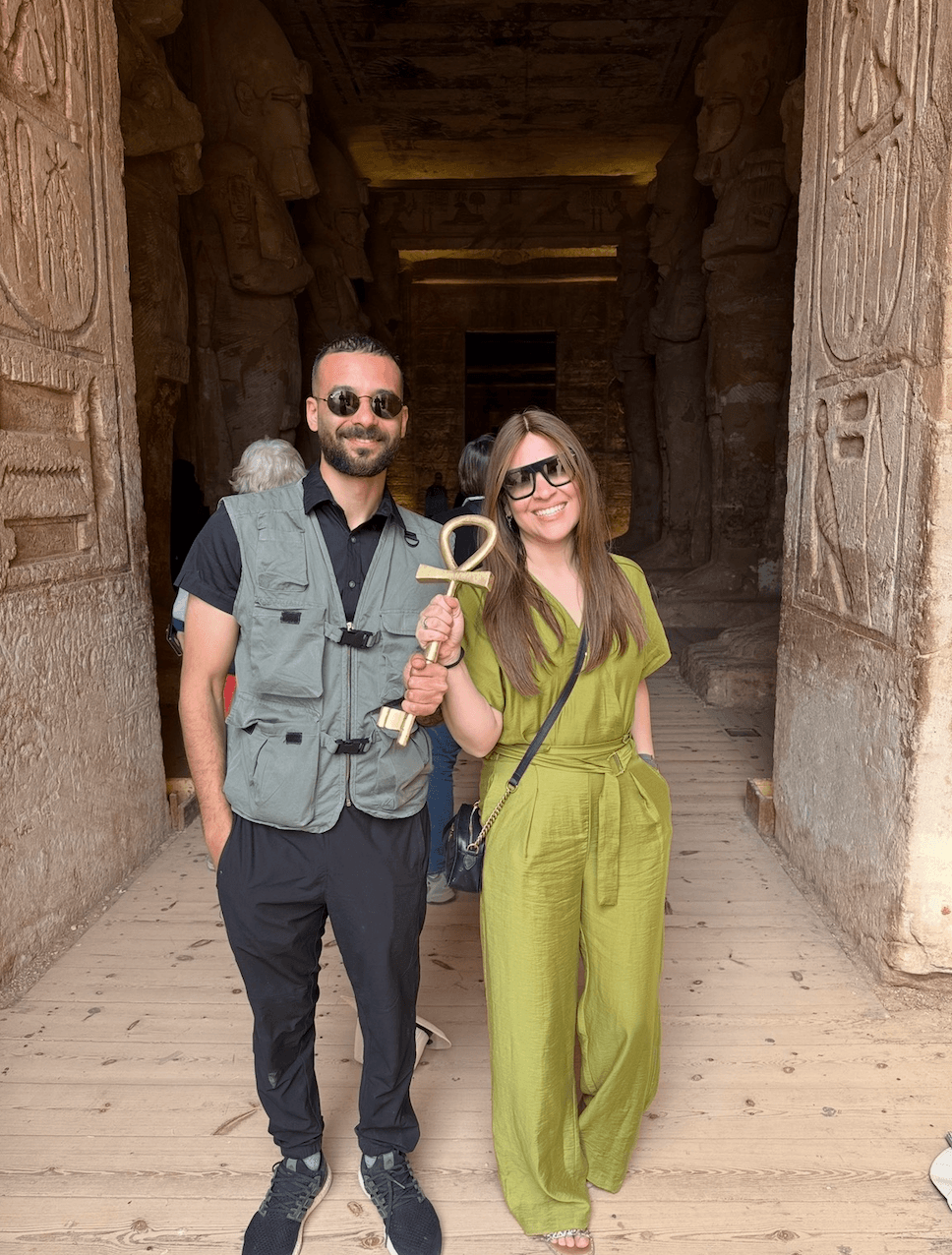 Tour guide and traveler holding ankh key at Nefertari temple entrance with hieroglyphic columns