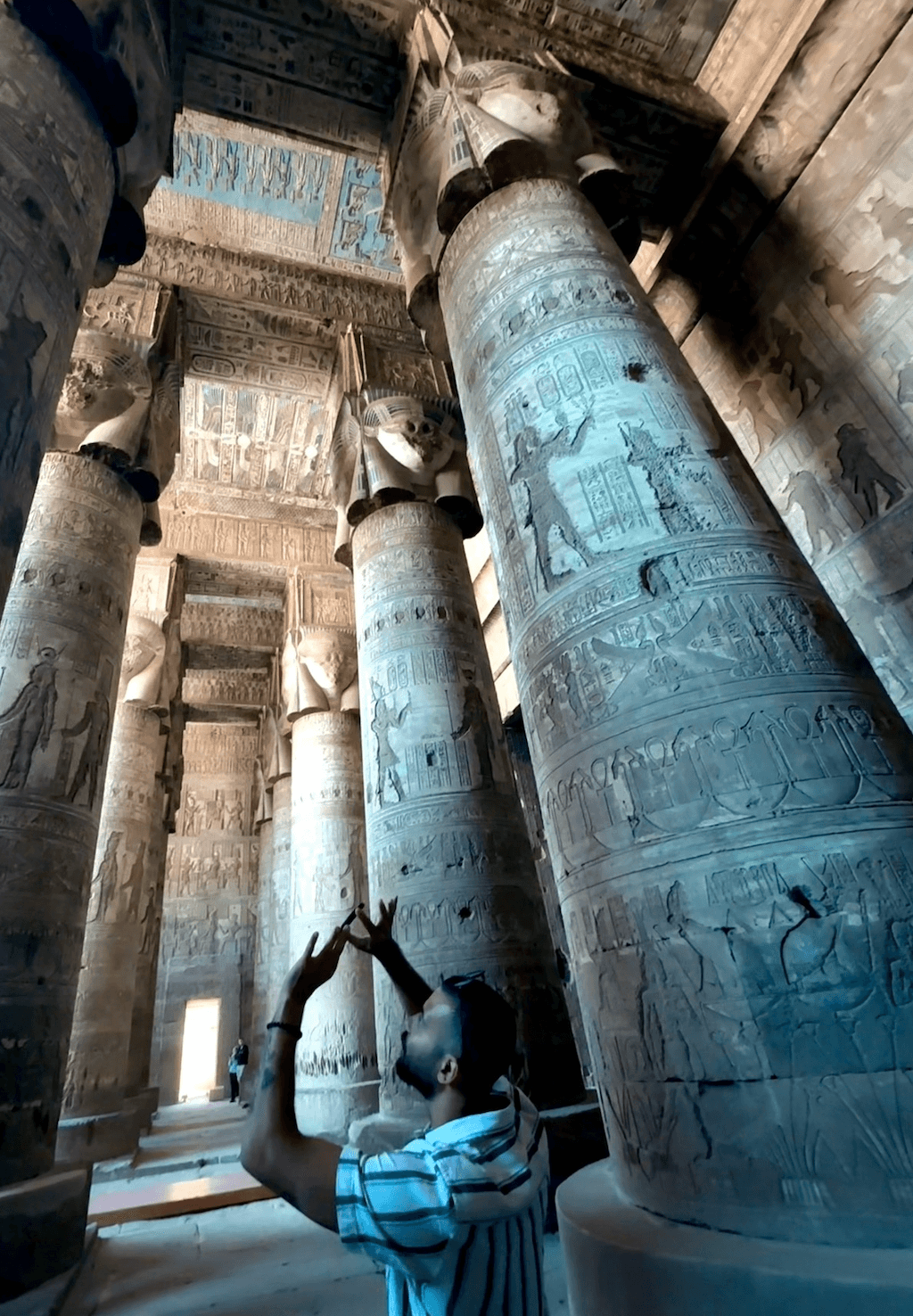 Tour guide showing hypostyle hall columns with Hathor faces at Dendera Temple