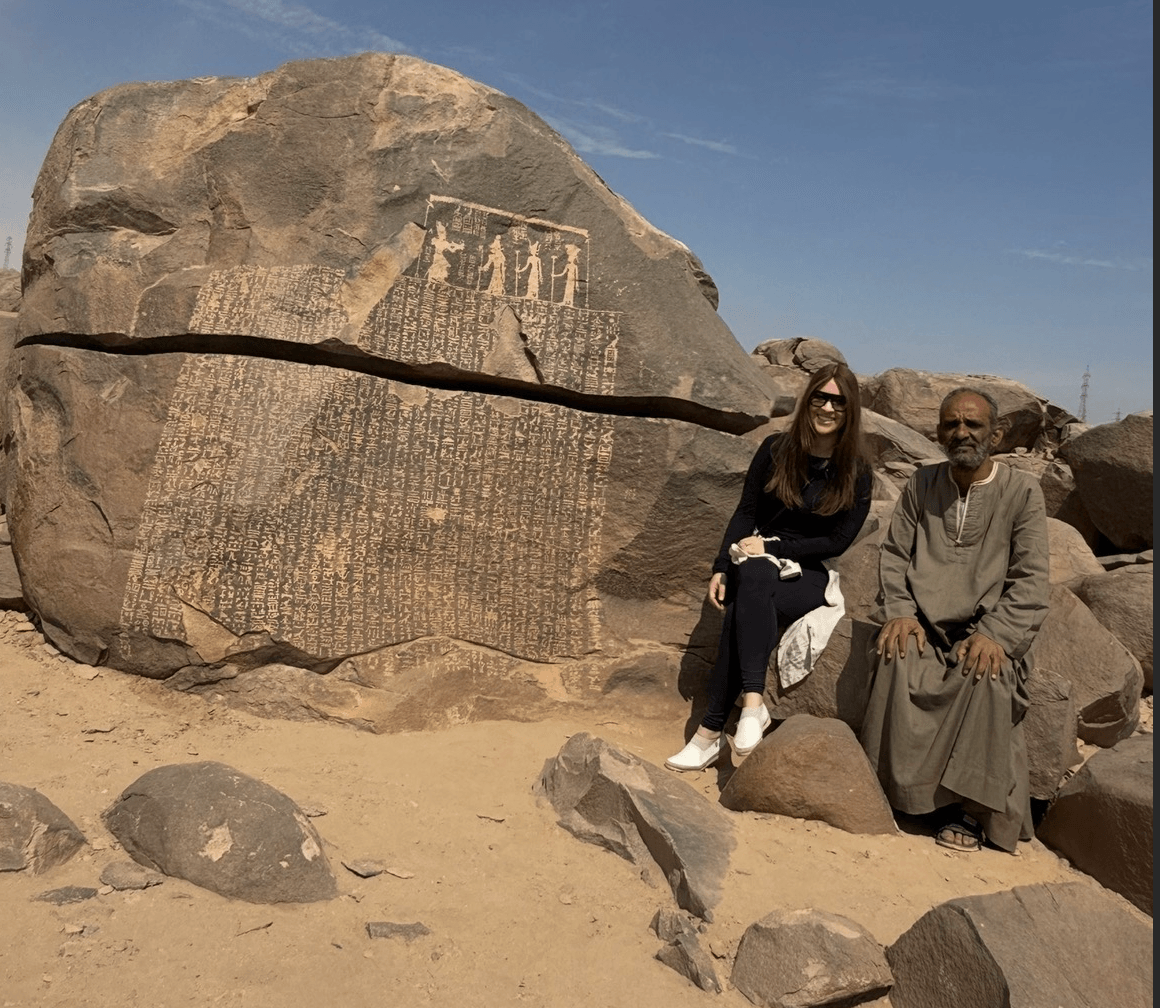 Female tourist with local Egyptian guide at Famine Stele hieroglyphic site in Aswan showing importance of guided tours