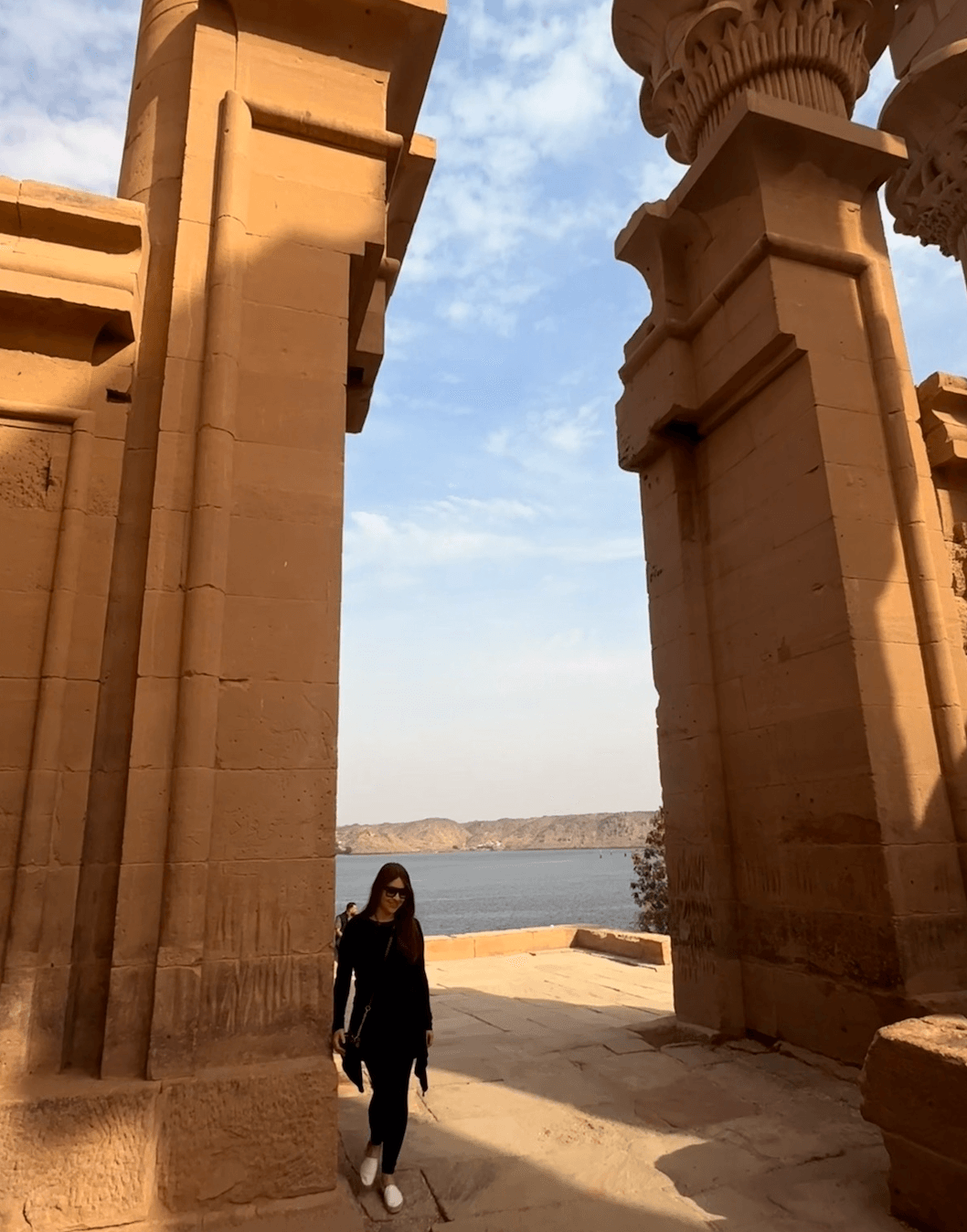 Massive ancient Egyptian temple columns at Philae Temple with the Nile River visible through the colonnade